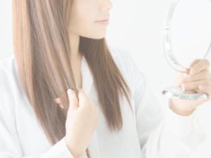 自分の髪を鏡で見る女性