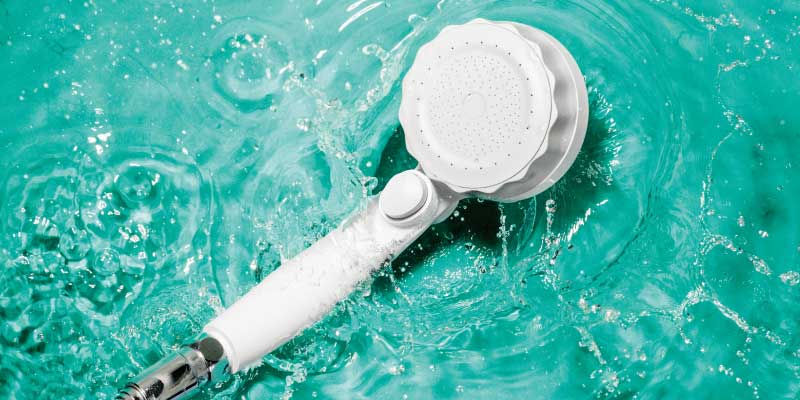 水しぶきをあげる水面と白いシャワーヘッド