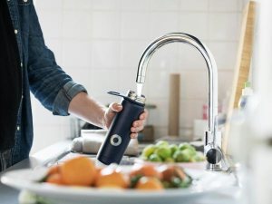 キッチンの蛇口から水筒に水をくむ人