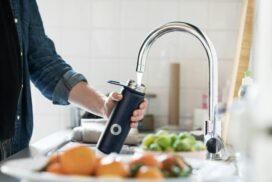キッチンの蛇口から水筒に水をくむ人