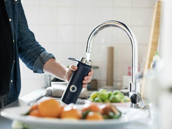 キッチンの蛇口から水筒に水をくむ人