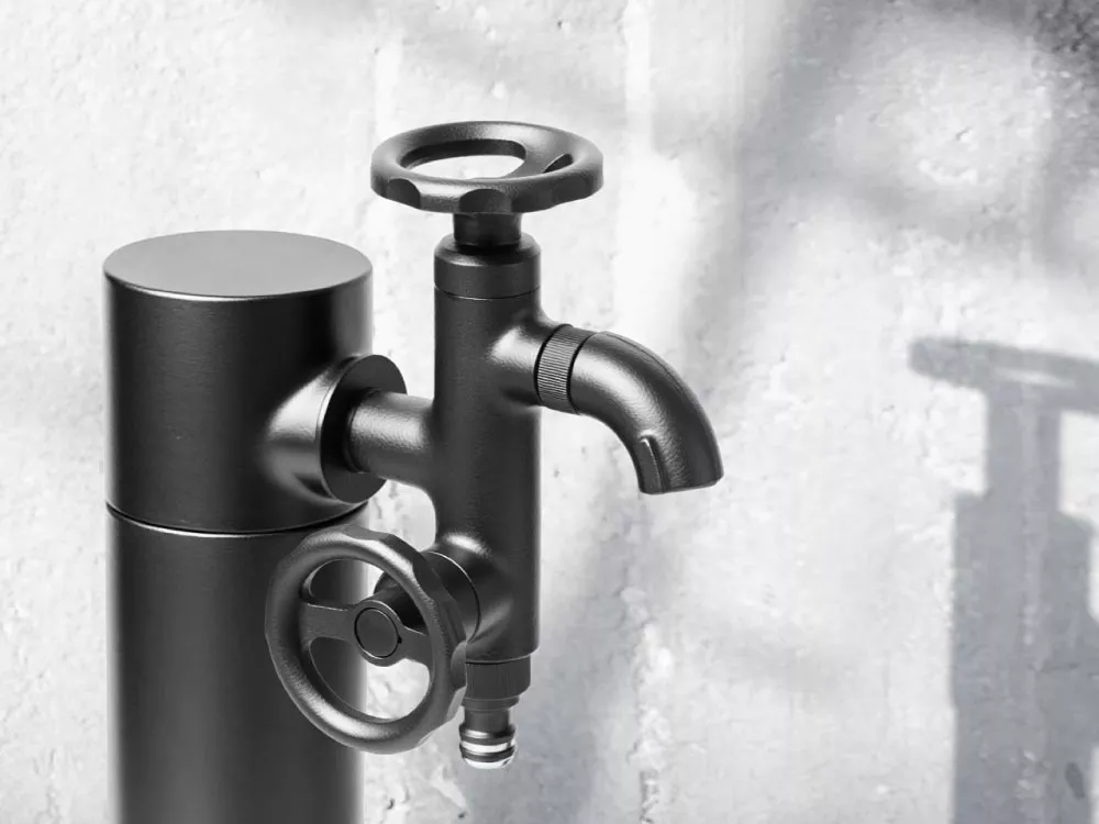 二口横水栓ウォーターワークス（マットブラック）と黒い水栓柱をコンクリート外壁前に設置したイメージ